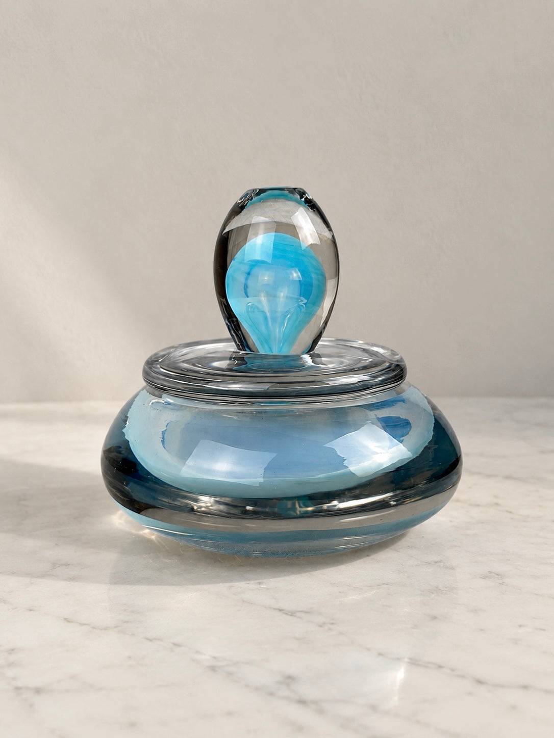 Murano art glass lidded dish with a rounded blue and smoky grey glass body, clear glass cover and sculptural turquoise-blue finial.