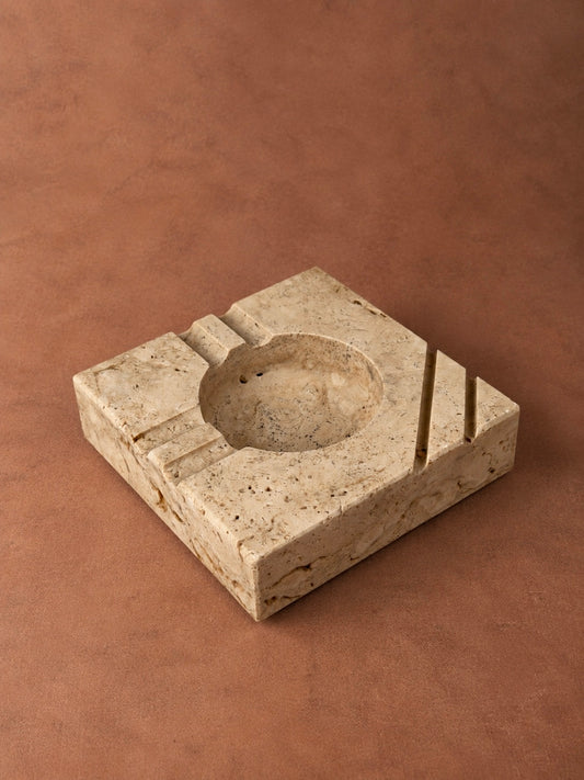 Square travertine ashtray attributed to Enzo Mari for Fratelli Mannelli, featuring a hemispherical bowl and geometric carved grooves.