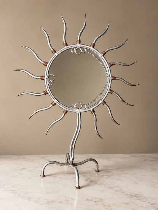Postmodern freestanding metal sunburst mirror with curved silver-tone rays, copper wire detailing and a sculptural four-footed stand.