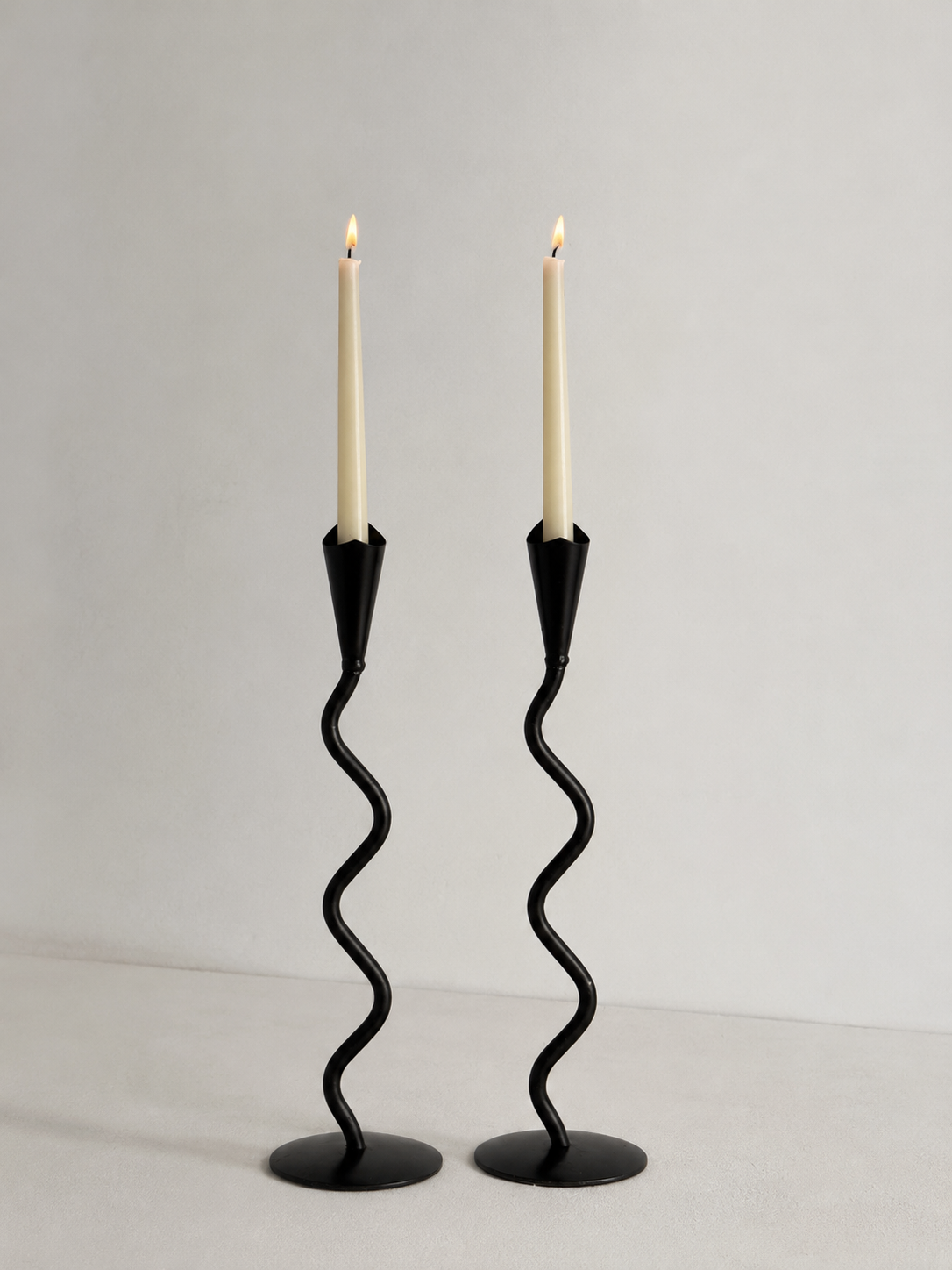 Pair of hand forged iron candlesticks with sculptural wavy stems