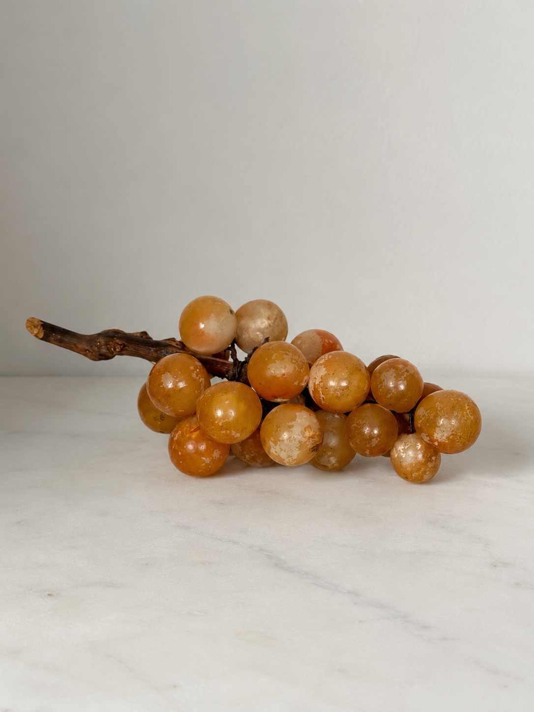 Vintage carved alabaster grape cluster sculpture on natural wood vine stem