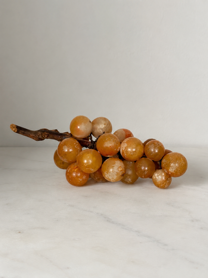Vintage carved alabaster grape cluster sculpture on natural wood vine stem
