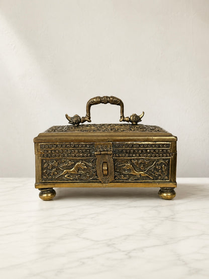 Ornate embossed brass lidded box with horse relief decoration, carrying handle and raised feet.